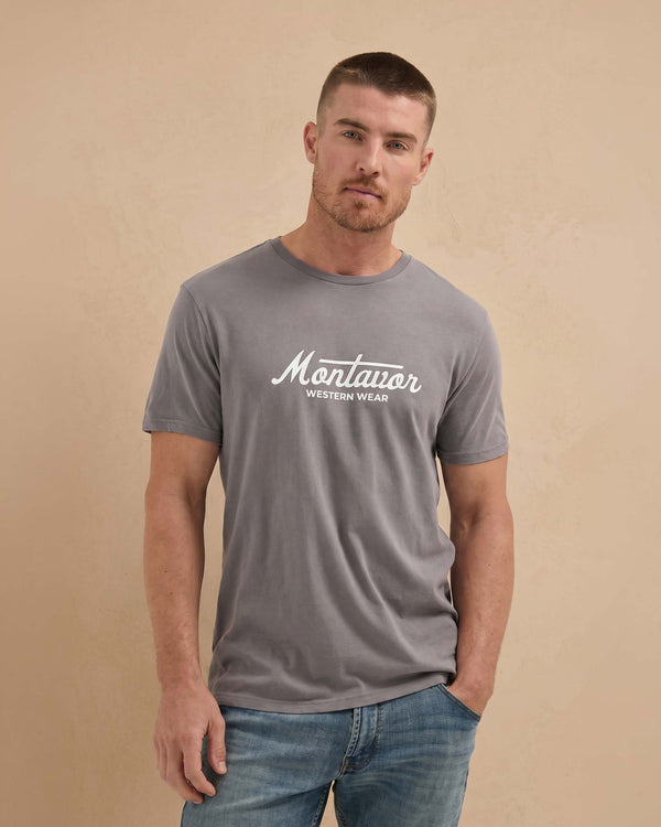 Man wearing a gray t-shirt with 'Montavor Western Wear' logo on a beige background