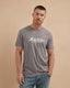 Man wearing a gray t-shirt with 'Montavor Western Wear' logo on a beige background