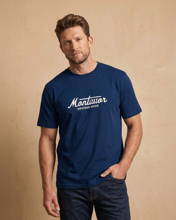 Man wearing a navy blue t-shirt with 'Montavor Western Wear' logo on a beige background