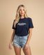 Woman wearing a navy blue t-shirt with 'Montavor' logo on a beige background