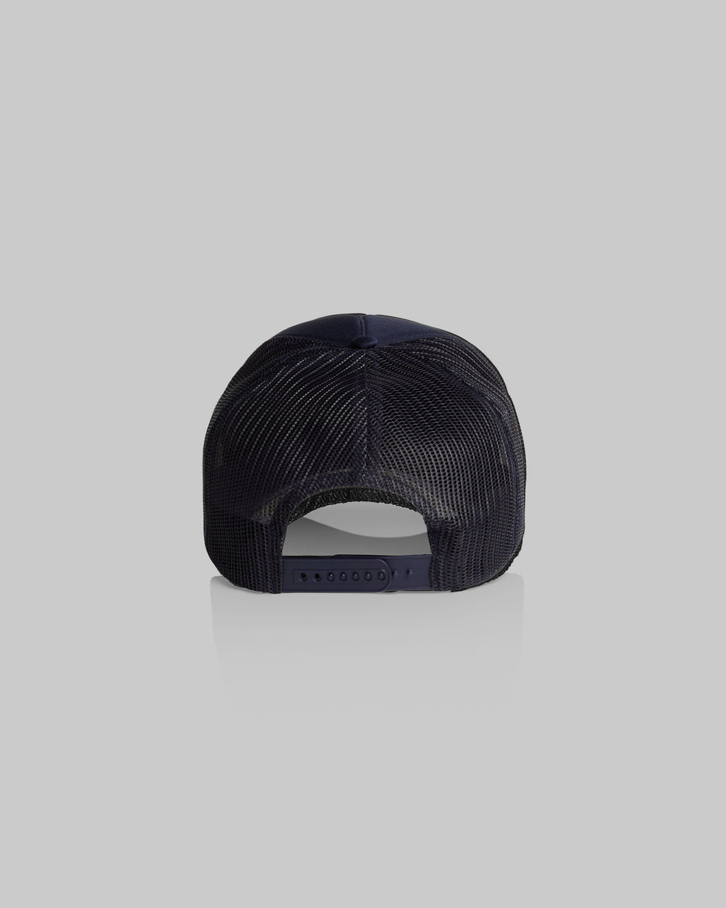 A rear view of a dark navy blue trucker-style cap with a mesh back, shown against a solid light gray background.