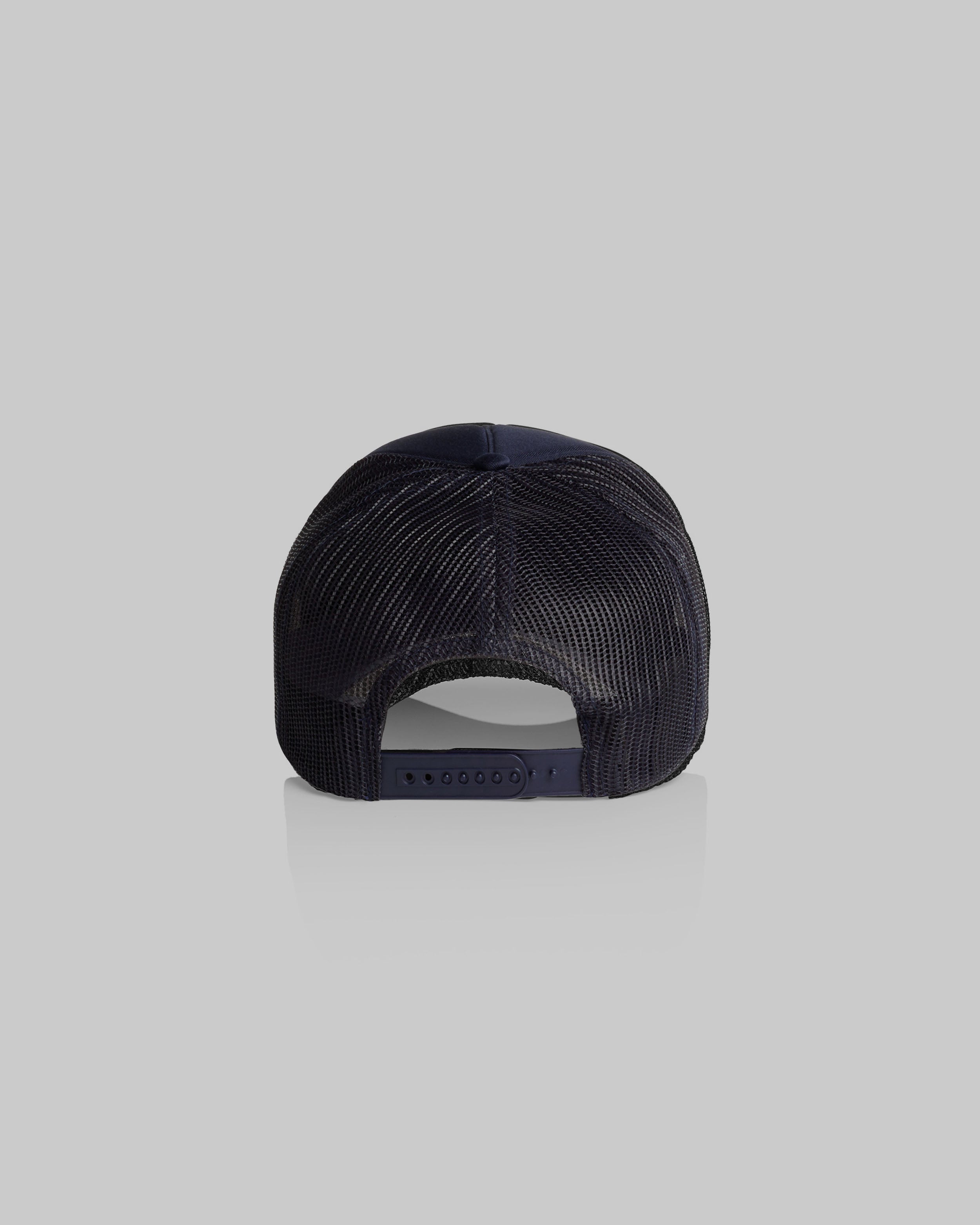 A rear view of a dark navy blue trucker-style cap with a mesh back, shown against a solid light gray background.