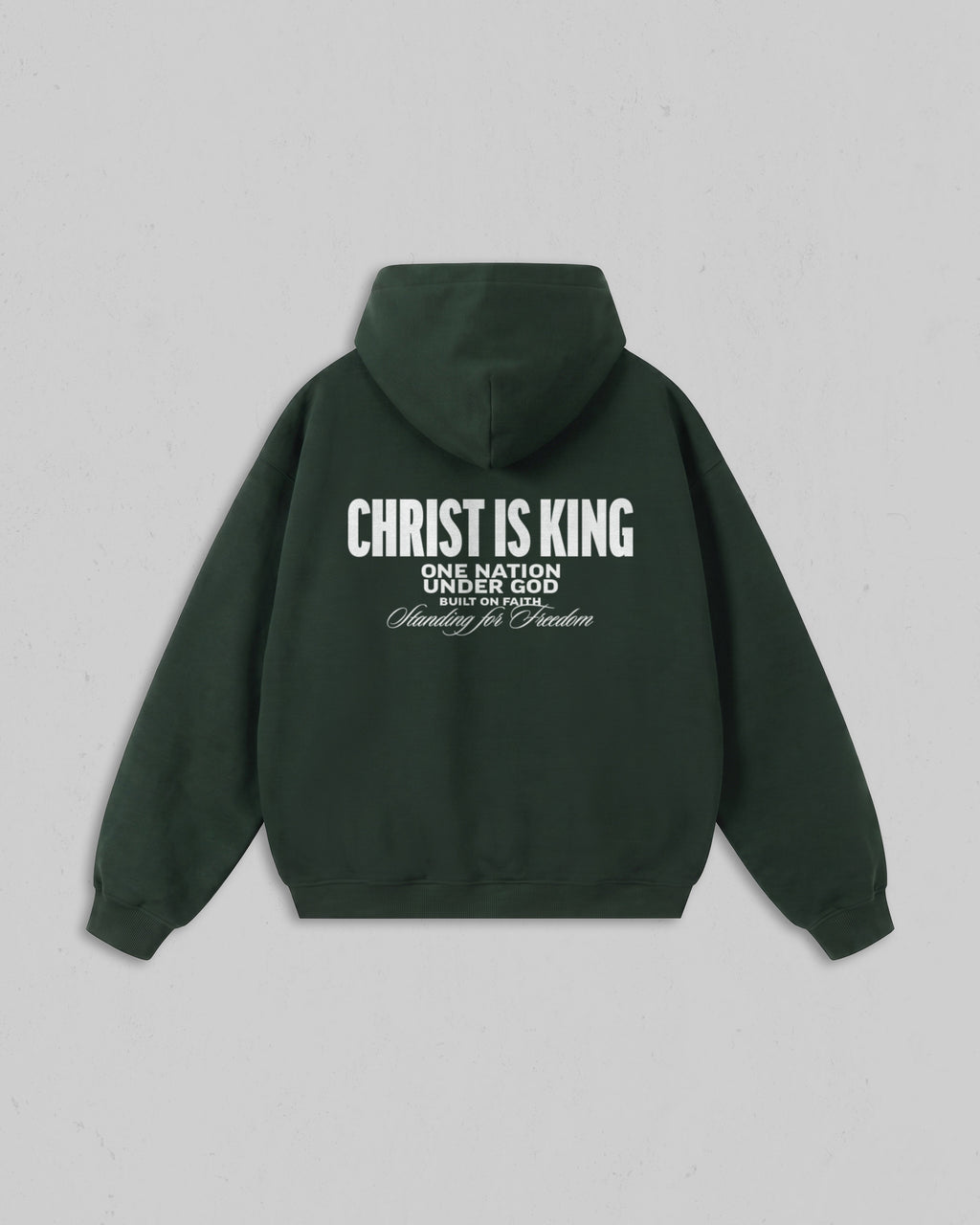 A dark forest green hoodie shown from the back, featuring white printed text that reads 'CHRIST IS KING' with smaller text below reading 'ONE NATION UNDER GOD' and 'Standing for Freedom'. The hoodie is displayed flat against a neutral light gray background.