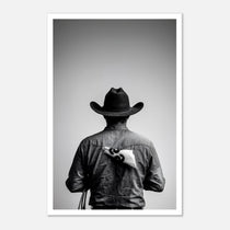Black and white photograph of a rodeo cowboy viewed from behind wearing a western hat with a numbered rodeo tag pinned to his shirt after competition.