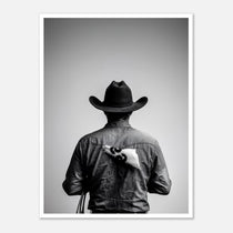 Black and white photograph of a rodeo cowboy viewed from behind wearing a western hat with a numbered rodeo tag pinned to his shirt after competition.