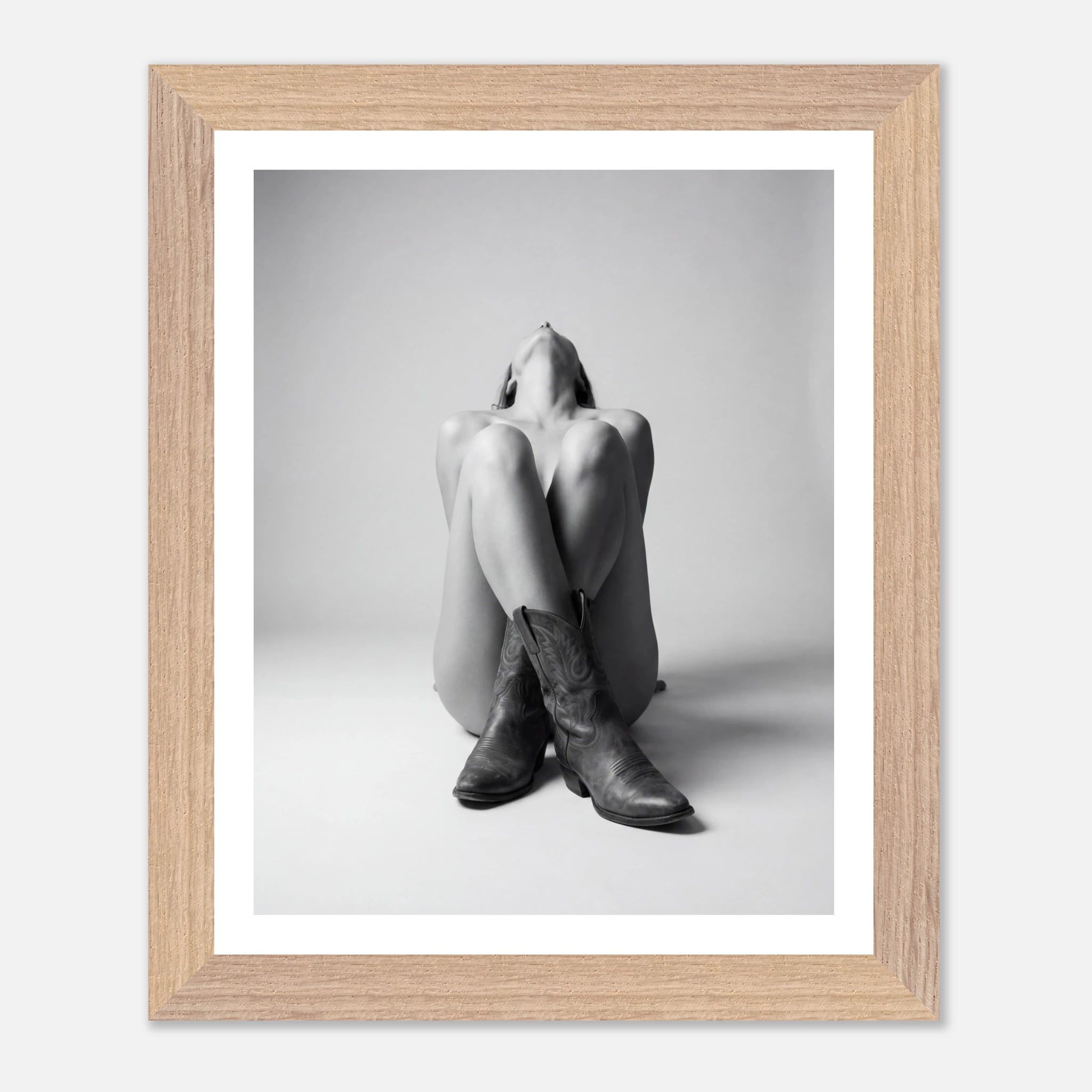 Framed black and white photo of a person wearing cowboy boots on a light gray background