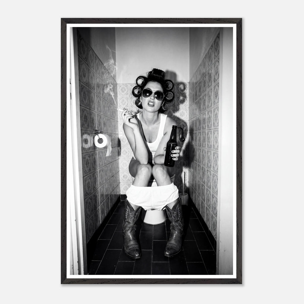 Black and white photograph of a rebellious cowgirl wearing cowboy boots and sunglasses sitting in a tiled restroom holding a cigarette and beer.