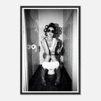 Black and white photograph of a rebellious cowgirl wearing cowboy boots and sunglasses sitting in a tiled restroom holding a cigarette and beer.