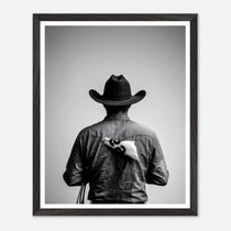 Black and white photograph of a rodeo cowboy viewed from behind wearing a western hat with a numbered rodeo tag pinned to his shirt after competition.