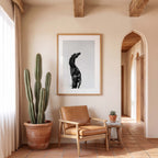 Living room with a cactus plant, brown leather chair, and framed artwork on a beige wall.