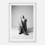 Person wearing a hoodie and boots sitting on the floor with a white frame.