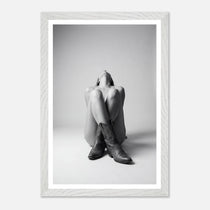 Person wearing a hoodie and boots sitting on the floor with a white frame.
