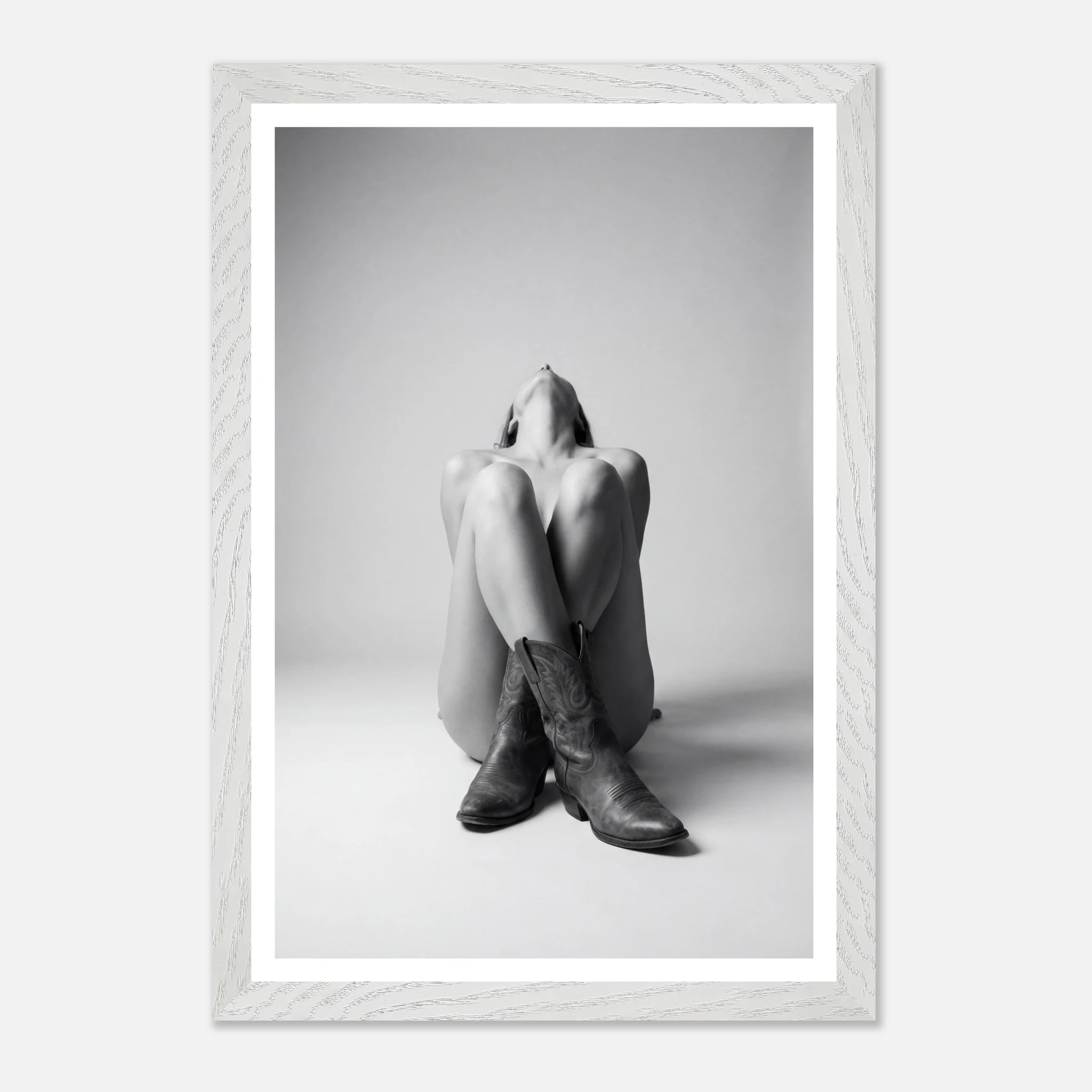 Person wearing a hoodie and boots sitting on the floor with a white frame.