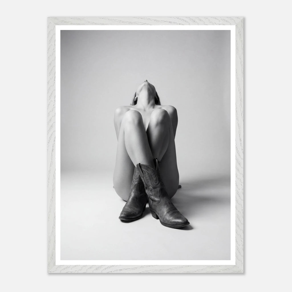 Person wearing cowboy boots sitting on the floor with a white frame.