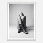 Person wearing cowboy boots sitting on the floor with a white frame.