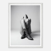 Person wearing cowboy boots sitting on the floor with a white frame.