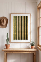 Framed artwork on a wall with a wooden table, potted plants, and a hat.