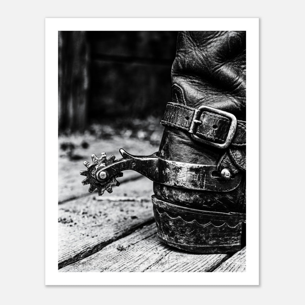 Black and white close up of a cowboy boot with metal spur on wooden floor, western ranch wall art.