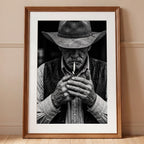 Black and white portrait of a cowboy lighting a cigarette wearing a hat, western wall art.
