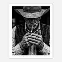 Black and white portrait of a cowboy lighting a cigarette wearing a hat, western wall art.
