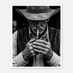 Black and white portrait of a cowboy lighting a cigarette wearing a hat, western wall art.