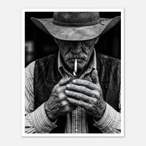 Black and white portrait of a cowboy lighting a cigarette wearing a hat, western wall art.