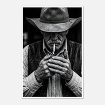 Black and white portrait of a cowboy lighting a cigarette wearing a hat, western wall art.