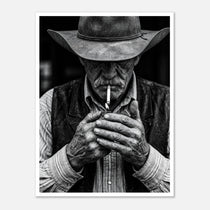 Black and white portrait of a cowboy lighting a cigarette wearing a hat, western wall art.