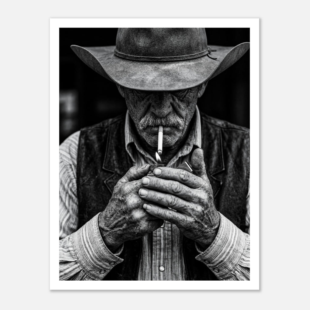 Black and white portrait of a cowboy lighting a cigarette wearing a hat, western wall art.