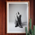 Black and white fine art poster of a seated cowgirl figure wearing classic cowboy boots against a minimalist studio background, creating a dramatic western-inspired composition.