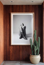Black and white fine art poster of a seated cowgirl figure wearing classic cowboy boots against a minimalist studio background, creating a dramatic western-inspired composition.