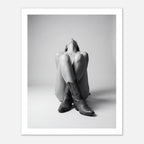 Black and white fine art poster of a seated cowgirl figure wearing classic cowboy boots against a minimalist studio background, creating a dramatic western-inspired composition.