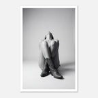 Black and white fine art poster of a seated cowgirl figure wearing classic cowboy boots against a minimalist studio background, creating a dramatic western-inspired composition.