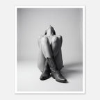 Black and white fine art poster of a seated cowgirl figure wearing classic cowboy boots against a minimalist studio background, creating a dramatic western-inspired composition.