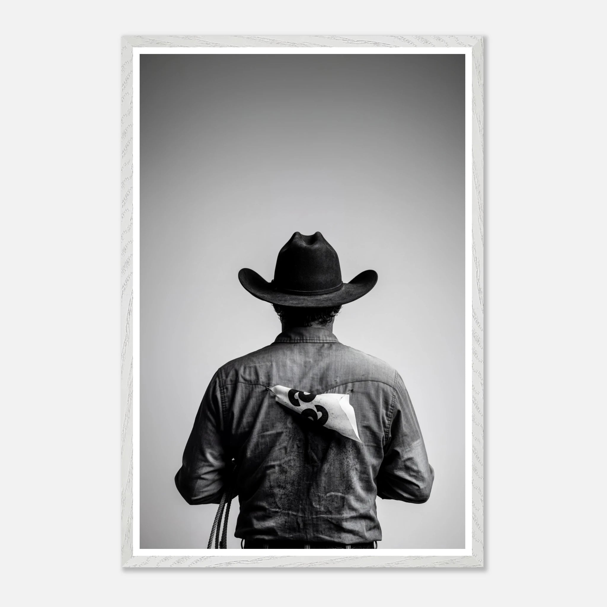 Black and white photograph of a rodeo cowboy viewed from behind wearing a western hat with a numbered rodeo tag pinned to his shirt after competition.