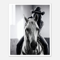 Black and white photograph of a cowgirl riding a horse head on wearing a cowboy hat, western equestrian wall art.