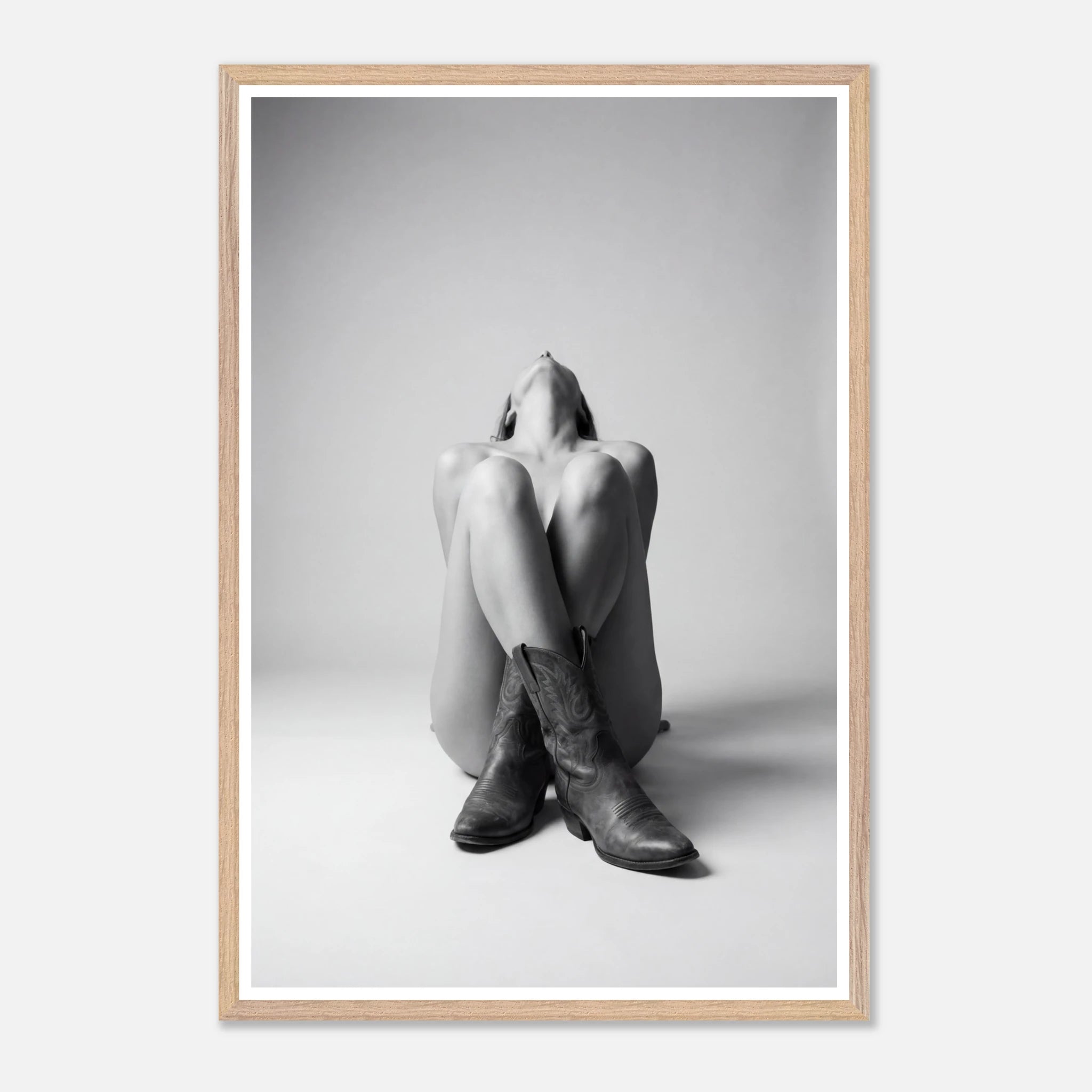 Framed black and white art print of a person sitting with cowboy boots on a plain background