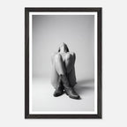 Framed black and white photo of a person sitting with legs crossed wearing cowboy boots.