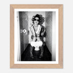 Black and white photograph of a rebellious cowgirl wearing cowboy boots and sunglasses sitting in a tiled restroom holding a cigarette and beer.