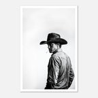Black and white photograph of a rodeo cowboy wearing a western hat and cigarette, turning toward the camera after competition, western cowboy wall art poster.