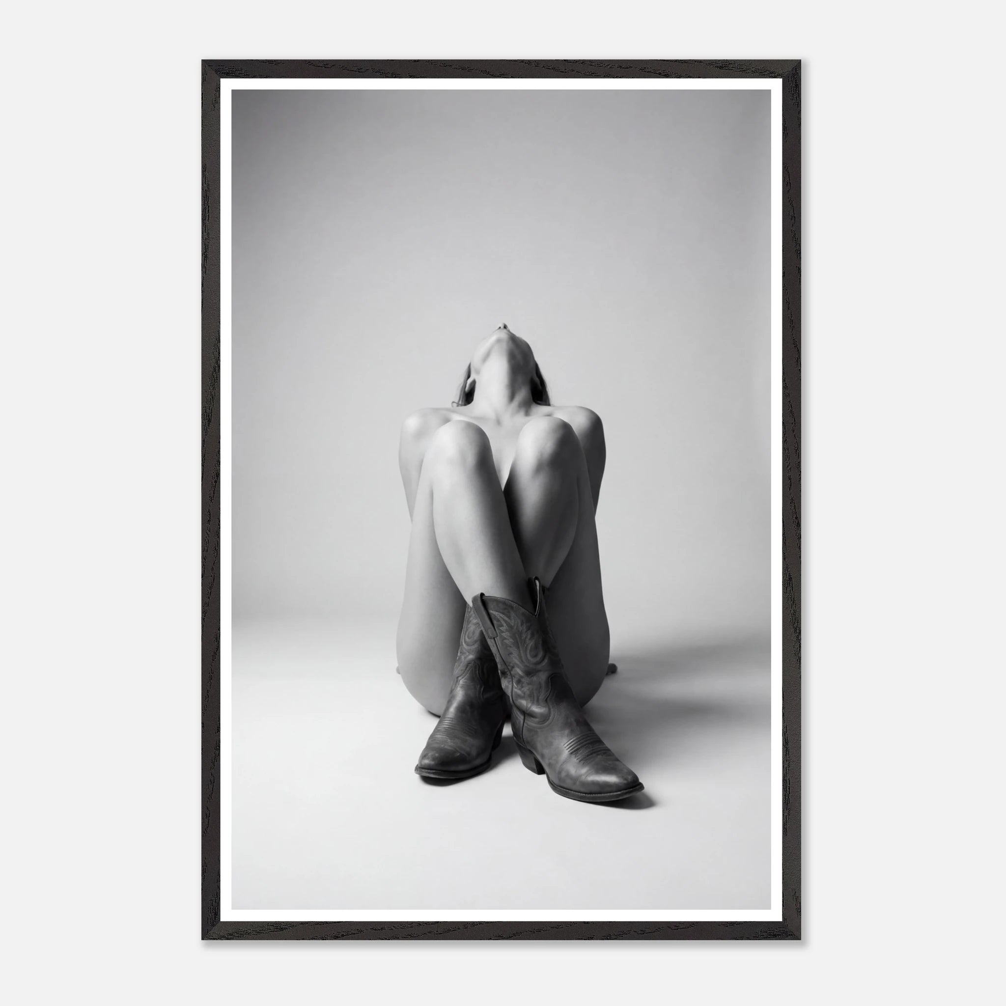 Framed black and white art print of a person sitting with cowboy boots on a plain background