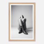 Framed black and white photo of a person sitting with legs crossed wearing cowboy boots.