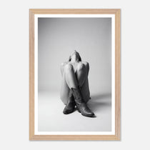 Framed black and white photo of a person sitting with legs crossed wearing cowboy boots.