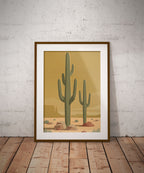 Minimalist Desert Poster Featuring Two Tall Saguaro Cacti In Soft Sage Green Against A Warm Golden Sky With Layered Sand Dunes And Desert Rocks, Mid Century Inspired Western Wall Art In Neutral Earth Tones.