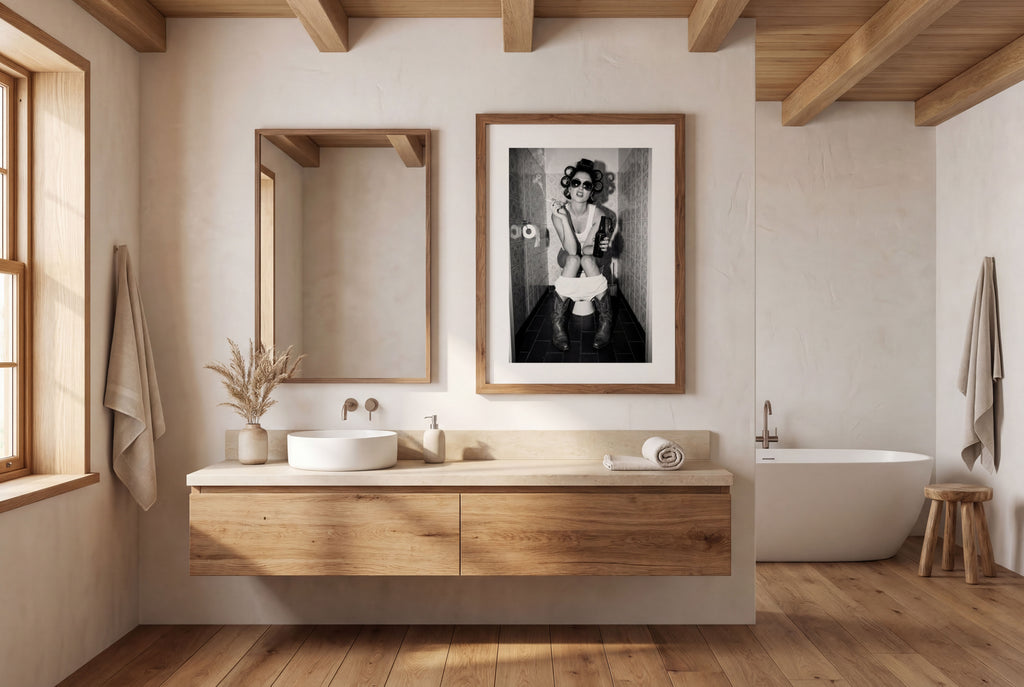 Black and white photograph of a rebellious cowgirl wearing cowboy boots and sunglasses sitting in a tiled restroom holding a cigarette and beer.