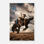 Cowboy riding a bucking horse at sunset with dust and dramatic sky, western rodeo wall art print