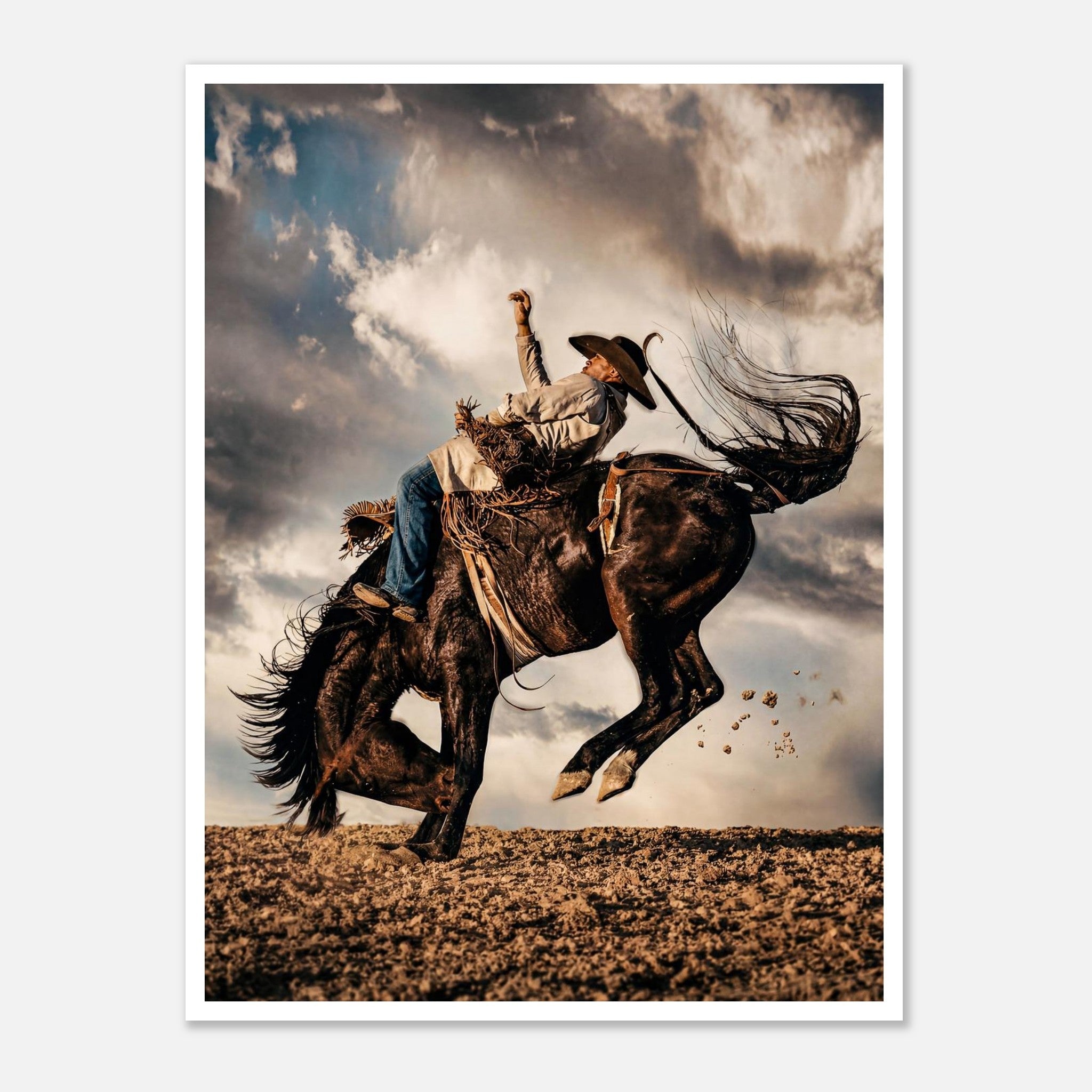 Cowboy riding a bucking horse at sunset with dust and dramatic sky, western rodeo wall art print