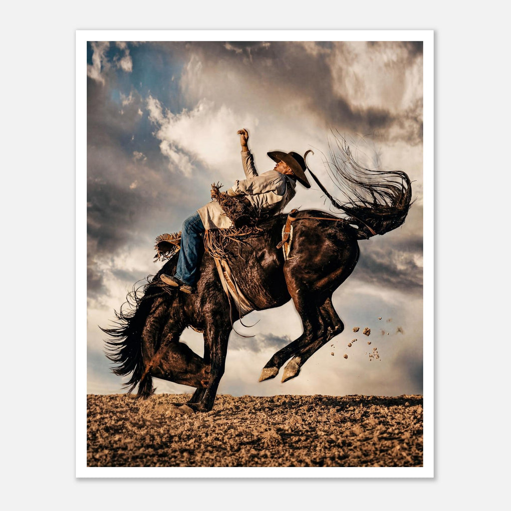 Cowboy riding a bucking horse at sunset with dust and dramatic sky, western rodeo wall art print