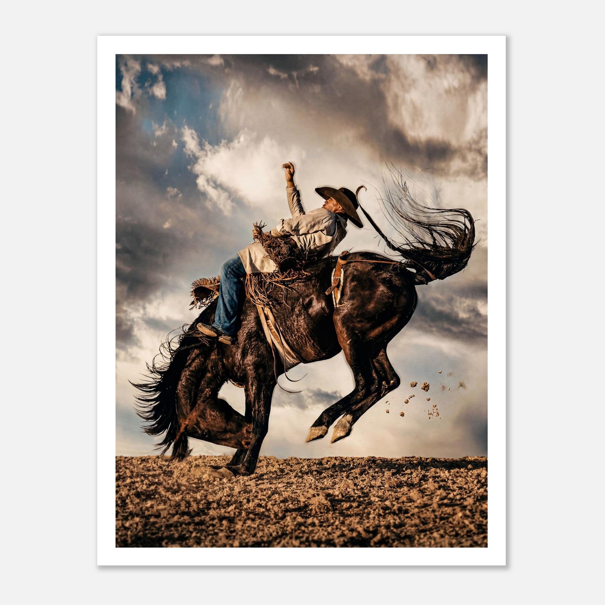 Cowboy riding a bucking horse at sunset with dust and dramatic sky, western rodeo wall art print