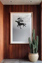Framed artwork of a horse in water on a wooden wall with a potted cactus.